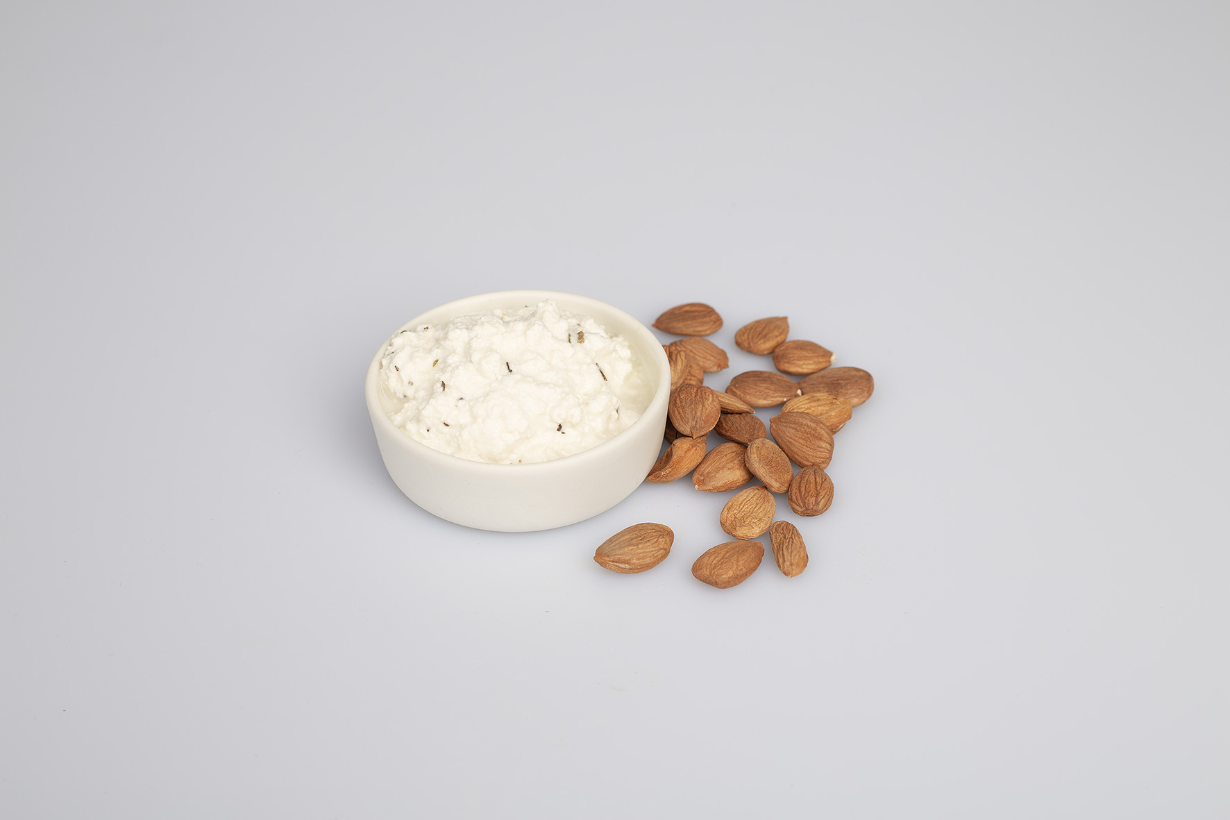 Pflanzlicher Hüttenkäse in einer Schüssel und einige Marillenweichkerne.