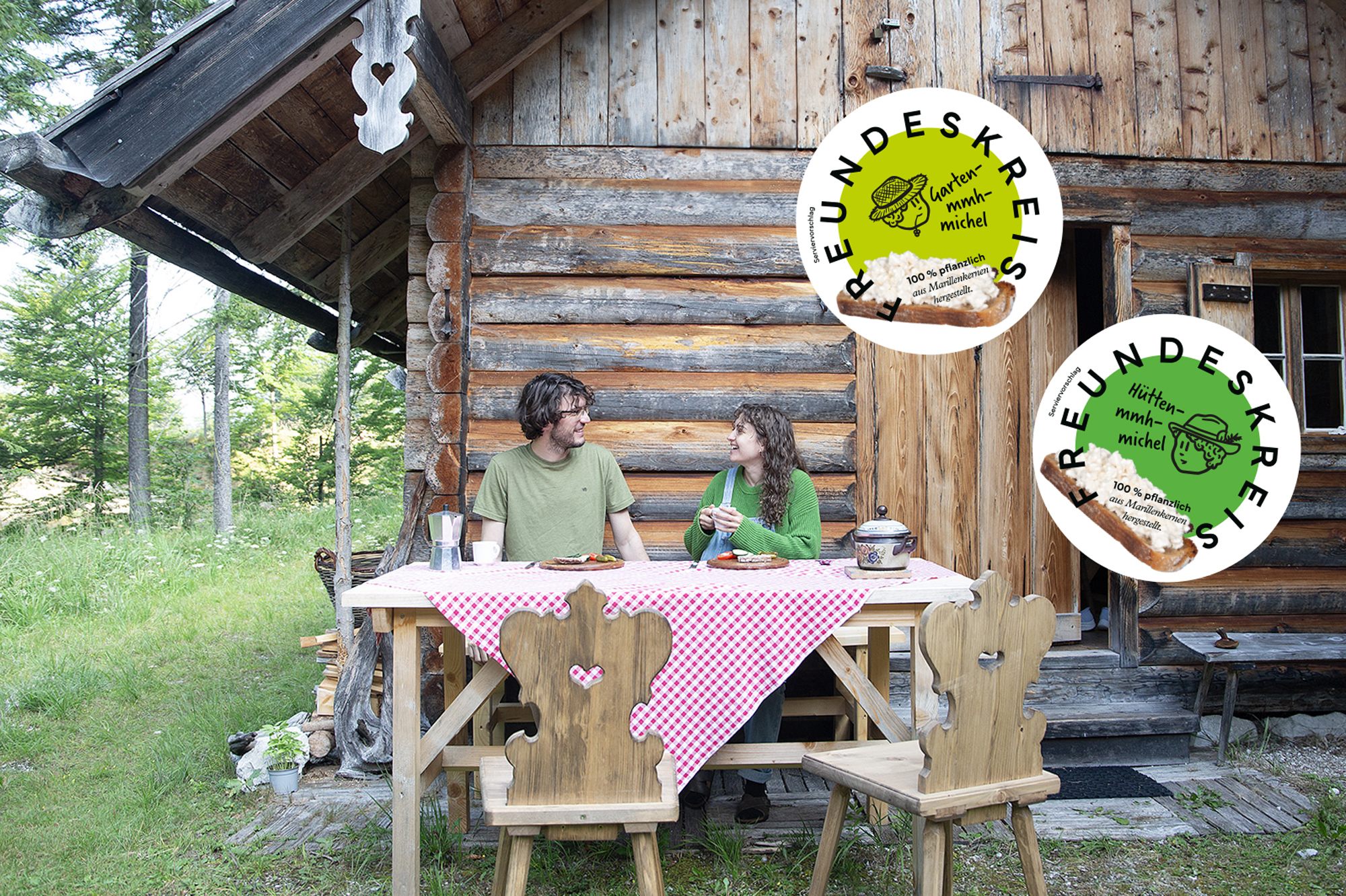 Ein Mann und eine Frau sitzen vor der Almhütte auf einer Bank und jausnen.